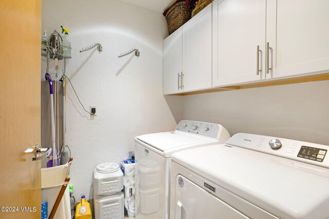 clothes washing area with cabinets and washer and clothes dryer