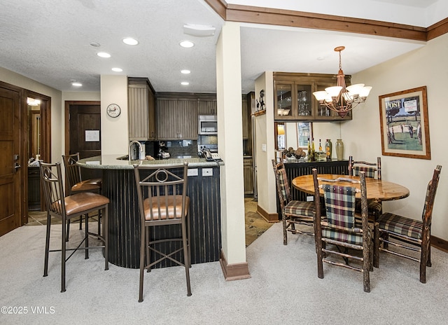 carpeted dining room with sink, a textured ceiling, and a notable chandelier