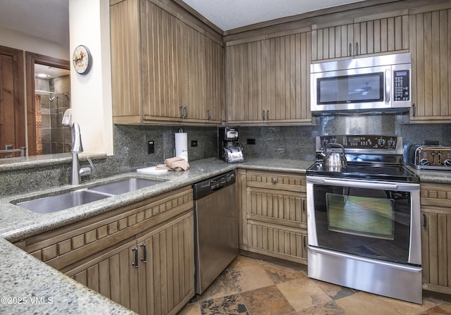 kitchen with light stone counters, sink, backsplash, and stainless steel appliances