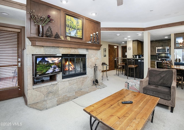 carpeted living room with a stone fireplace