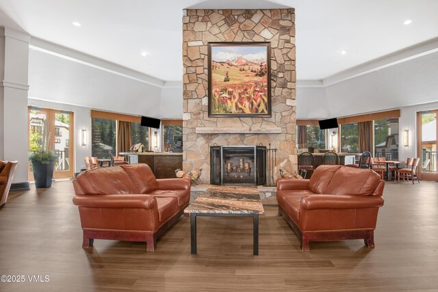 living room featuring a stone fireplace, a towering ceiling, and hardwood / wood-style flooring