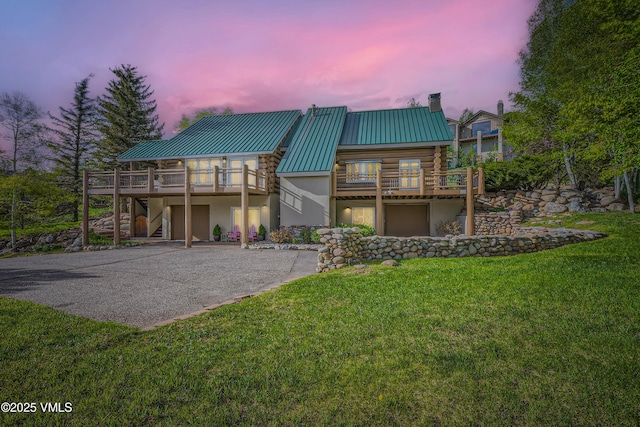 121 Hackamore Rd Unit B, Edwards, CO 81632 - back of house at dusk featuring driveway, log exterior, stairs, an attached garage, and metal roof