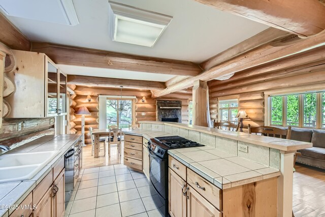 121 Hackamore Rd Unit B, Edwards, CO 81632 - kitchen featuring tile counters, black gas stove, rustic walls, a sink, and open floor plan