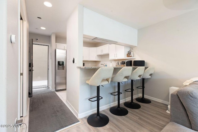 216 Main St Unit R316, Edwards, CO 81632 - kitchen with stainless steel fridge, a breakfast bar, light wood-style flooring, white cabinets, and a peninsula