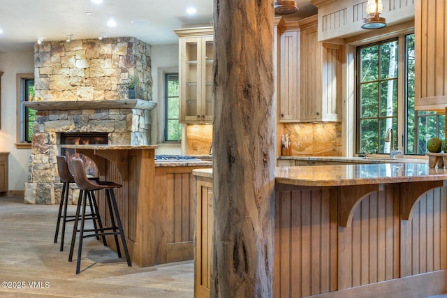 12 Cabin Creek Ln, Edwards, CO 81632 - bar area featuring healthy amount of natural light, light wood-type flooring, backsplash, and a stone fireplace