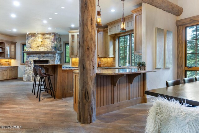 12 Cabin Creek Ln, Edwards, CO 81632 - kitchen with recessed lighting, a kitchen breakfast bar, light wood finished floors, glass insert cabinets, and light stone countertops