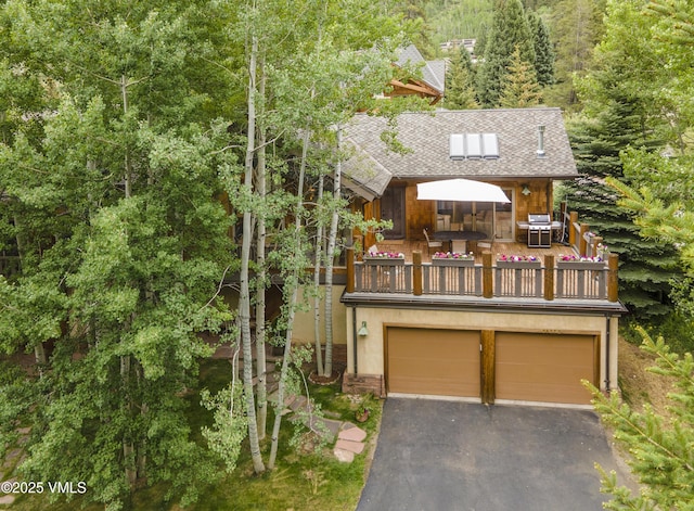 3827 Lupine Dr Unit B, Vail, CO 81657 - view of front of house with an attached garage, asphalt driveway, a balcony, and a forest view