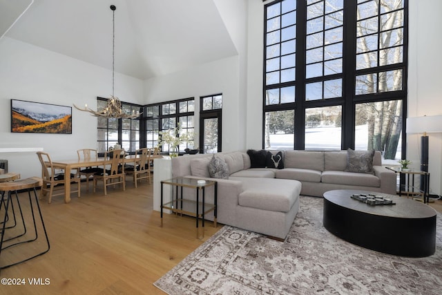 living room with an inviting chandelier, a towering ceiling, and wood-type flooring