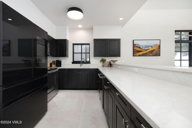 kitchen with stainless steel appliances, light stone countertops, and sink