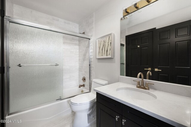 full bathroom featuring vanity, shower / bath combination with glass door, and toilet