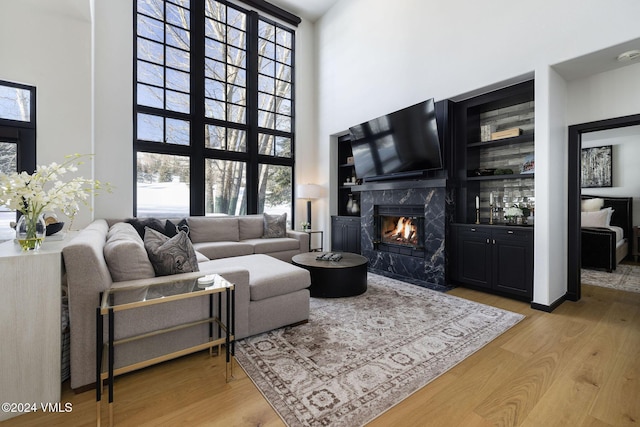 living room featuring a fireplace, light hardwood / wood-style flooring, and a high ceiling