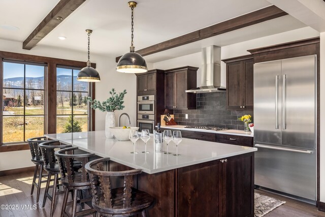 687 Hunters View Ln, Eagle, CO 81631 - kitchen featuring appliances with stainless steel finishes, beamed ceiling, wall chimney range hood, decorative backsplash, and dark wood-type flooring