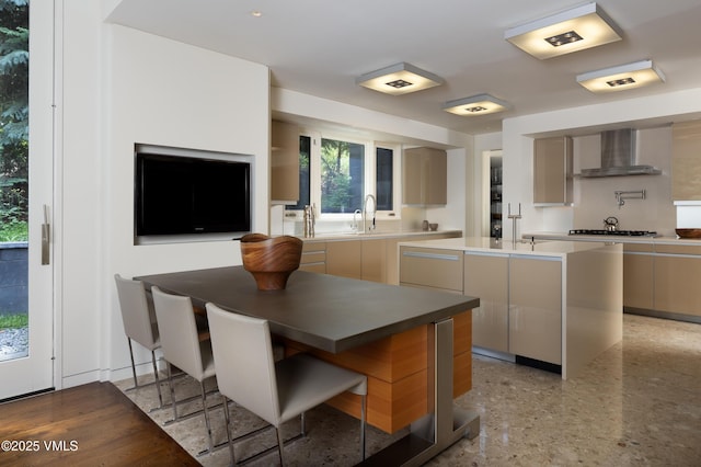 344 Beaver Dam Rd, Vail, CO 81657 - kitchen with wall chimney range hood, modern cabinets, a center island with sink, stainless steel gas cooktop, and plenty of natural light