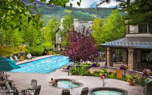 view of swimming pool with a mountain view, a community hot tub, and a patio area