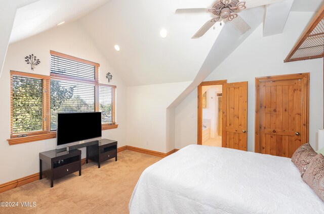 carpeted bedroom with ceiling fan, ensuite bathroom, and high vaulted ceiling