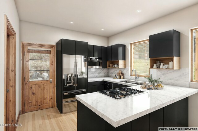 kitchen featuring sink, light hardwood / wood-style flooring, stainless steel appliances, tasteful backsplash, and kitchen peninsula