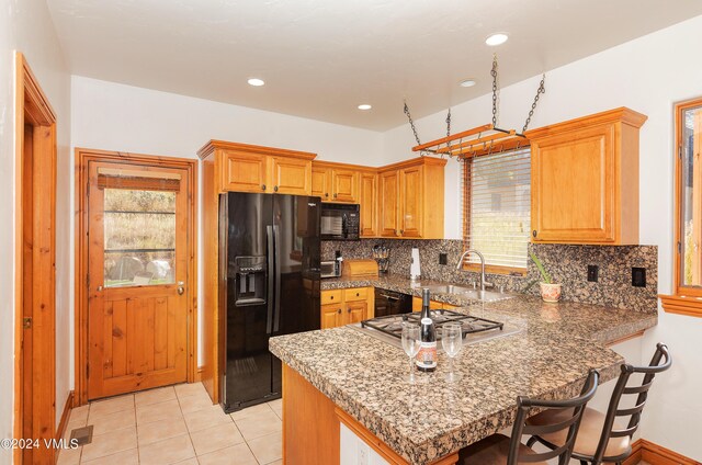 kitchen with tasteful backsplash, sink, black appliances, and kitchen peninsula