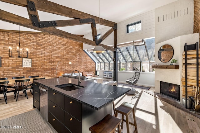 kitchen featuring light wood-style floors, open floor plan, a sink, and brick wall