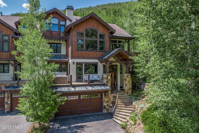 2417 Garmisch Dr Unit B, Vail, CO 81657 - view of front of house with asphalt driveway, an attached garage, a chimney, a standing seam roof, and a metal roof