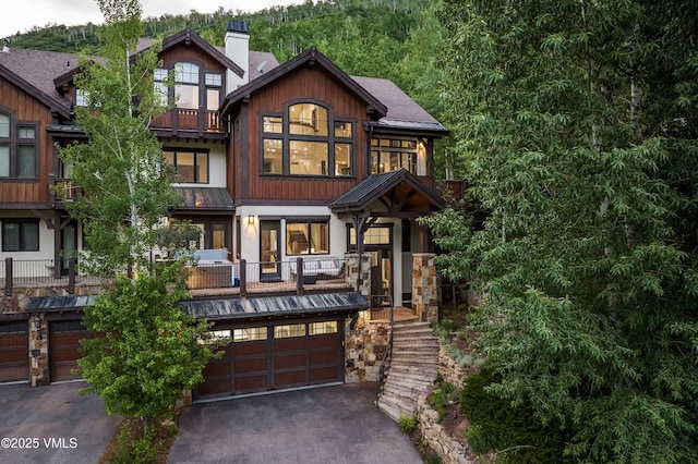 2417 Garmisch Dr Unit B, Vail, CO 81657 - view of front of home with asphalt driveway, a standing seam roof, a garage, a metal roof, and a chimney