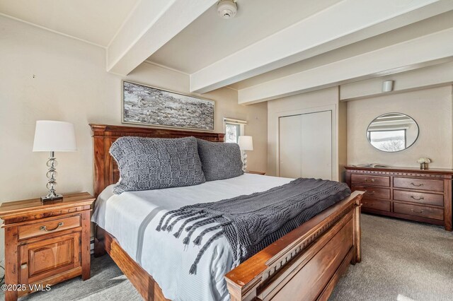 carpeted bedroom featuring a closet and beamed ceiling