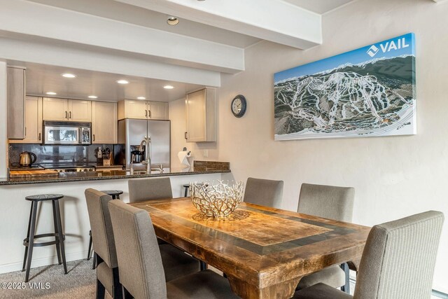 carpeted dining room featuring beam ceiling