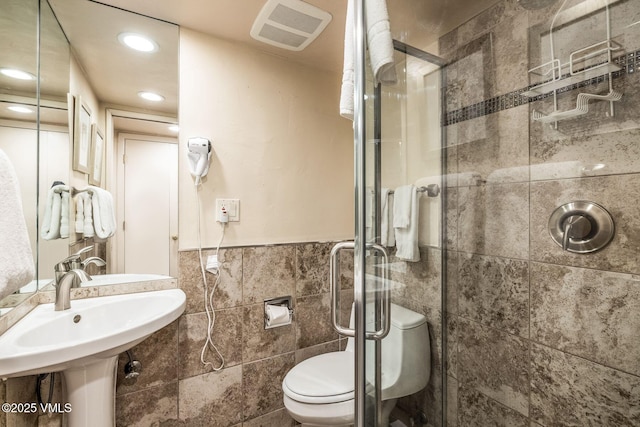 bathroom featuring sink, tile walls, an enclosed shower, and toilet