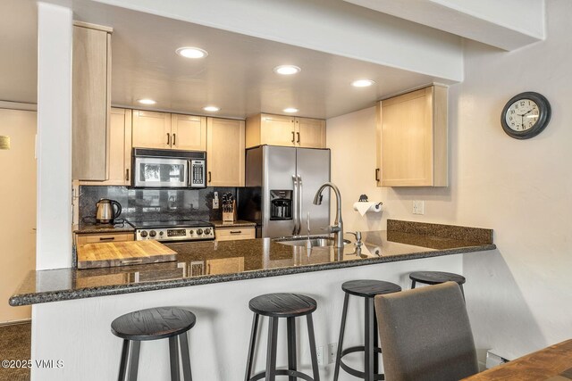 kitchen featuring appliances with stainless steel finishes, kitchen peninsula, sink, and dark stone counters