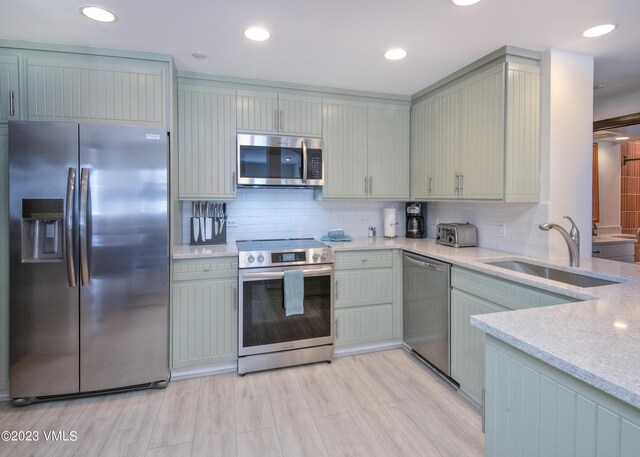 kitchen featuring sink, light hardwood / wood-style flooring, appliances with stainless steel finishes, gray cabinetry, and decorative backsplash