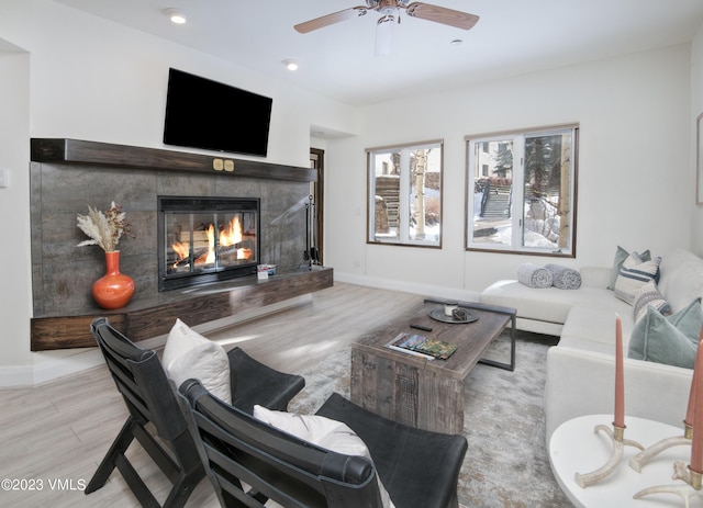 living room with light hardwood / wood-style flooring, a high end fireplace, and ceiling fan