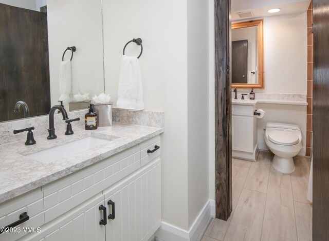 bathroom with vanity, toilet, and wood-type flooring