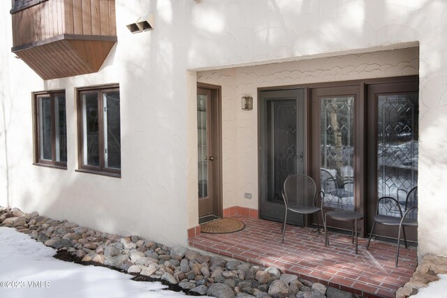 snow covered property entrance with a balcony and a patio area