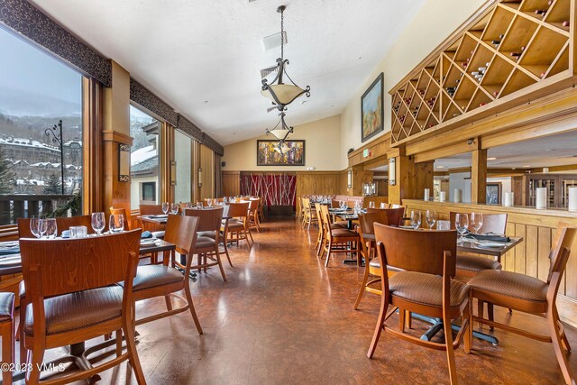 dining room with vaulted ceiling and wood walls