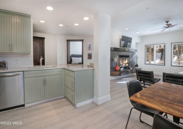 kitchen featuring sink, backsplash, stainless steel dishwasher, and green cabinets