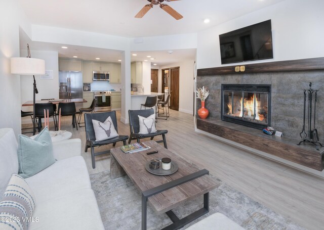 living room featuring a fireplace, light hardwood / wood-style floors, and ceiling fan