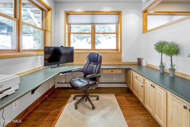 office featuring dark hardwood / wood-style flooring, built in desk, and a baseboard heating unit