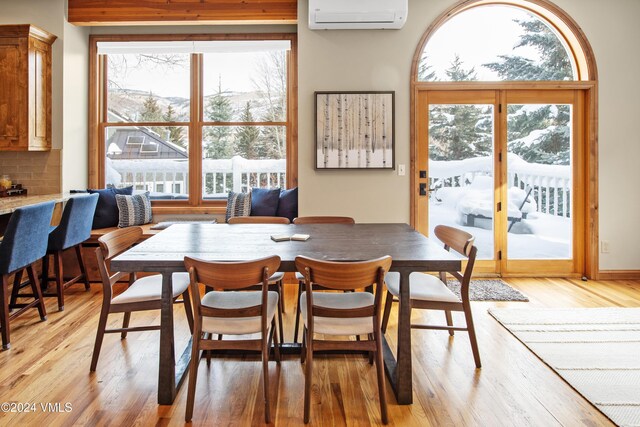 dining space featuring an AC wall unit and light wood-type flooring