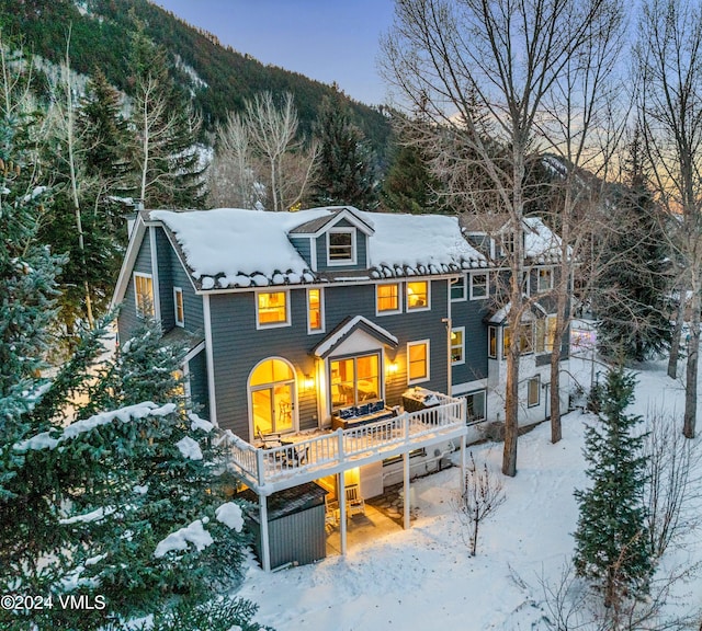 snow covered rear of property featuring a deck with mountain view