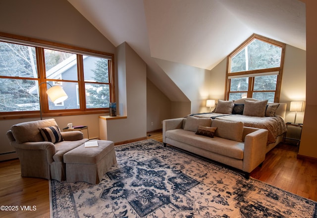 bedroom with multiple windows, hardwood / wood-style floors, vaulted ceiling, and a baseboard radiator