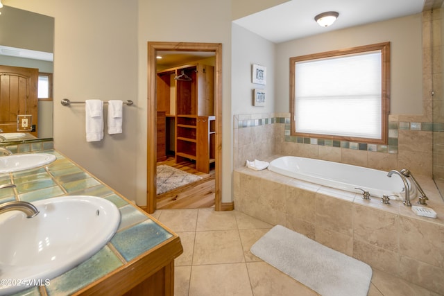 bathroom featuring vanity, tiled bath, and tile patterned flooring