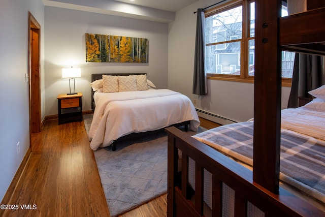 bedroom featuring a baseboard heating unit and light hardwood / wood-style flooring