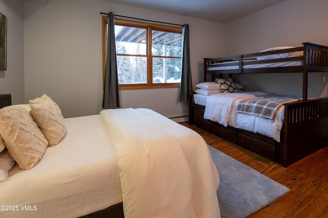 bedroom with dark hardwood / wood-style flooring and a baseboard heating unit