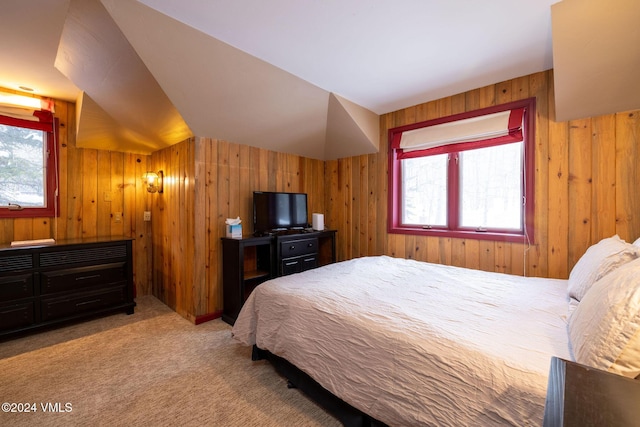 carpeted bedroom with multiple windows, vaulted ceiling, and wood walls