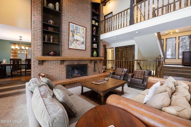 living room with a high ceiling, a brick fireplace, built in features, and a chandelier