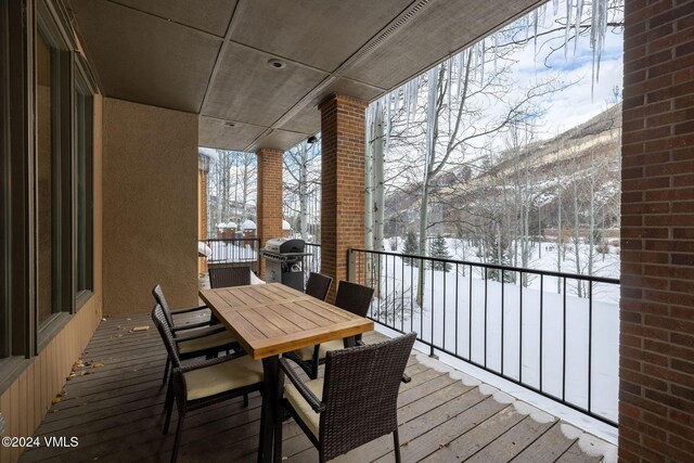 snow covered back of property with a mountain view and grilling area