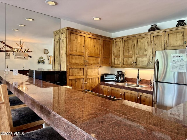 1100 N Frontage Rd Unit 1519, Vail, CO 81657 - kitchen featuring freestanding refrigerator, tile countertops, recessed lighting, brown cabinets, and a kitchen bar