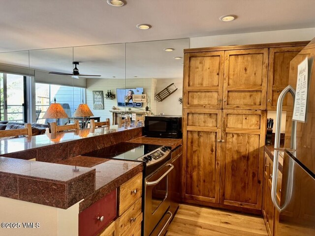 1100 N Frontage Rd Unit 1519, Vail, CO 81657 - kitchen featuring appliances with stainless steel finishes, tile counters, light wood-type flooring, brown cabinetry, and recessed lighting