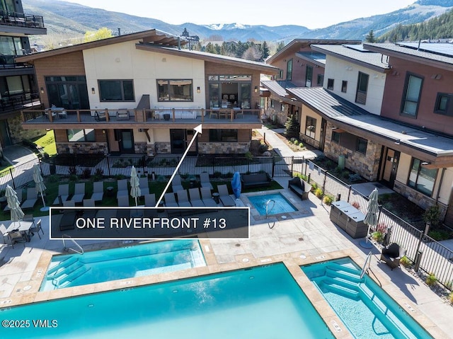 42 Riverfront Ln Unit Th-13, Avon, CO 81620 - rear view of house with a community hot tub, a mountain view, a community pool, and a fenced backyard