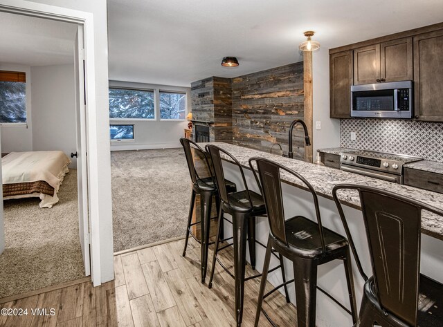 kitchen featuring sink, decorative backsplash, dark brown cabinetry, stainless steel appliances, and light carpet