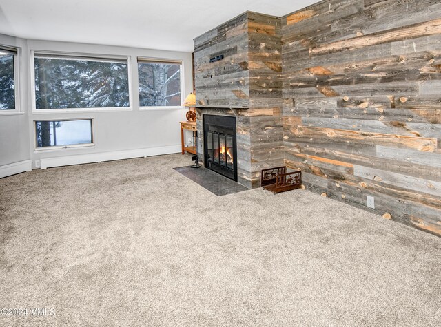 unfurnished living room featuring wooden walls and carpet flooring